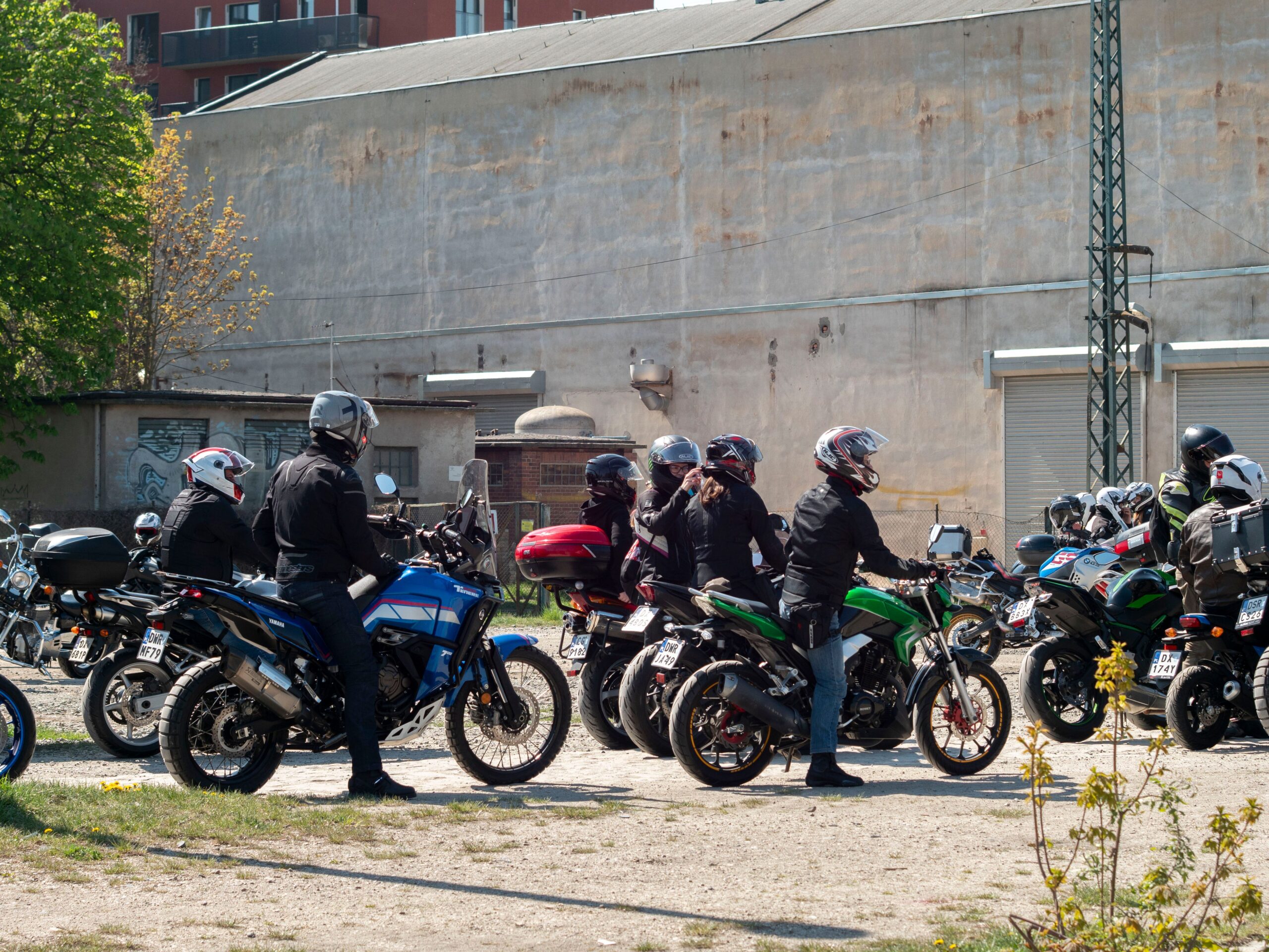 Group of motorcyclists on various bikes gathering outdoors in Wrocław, Poland.