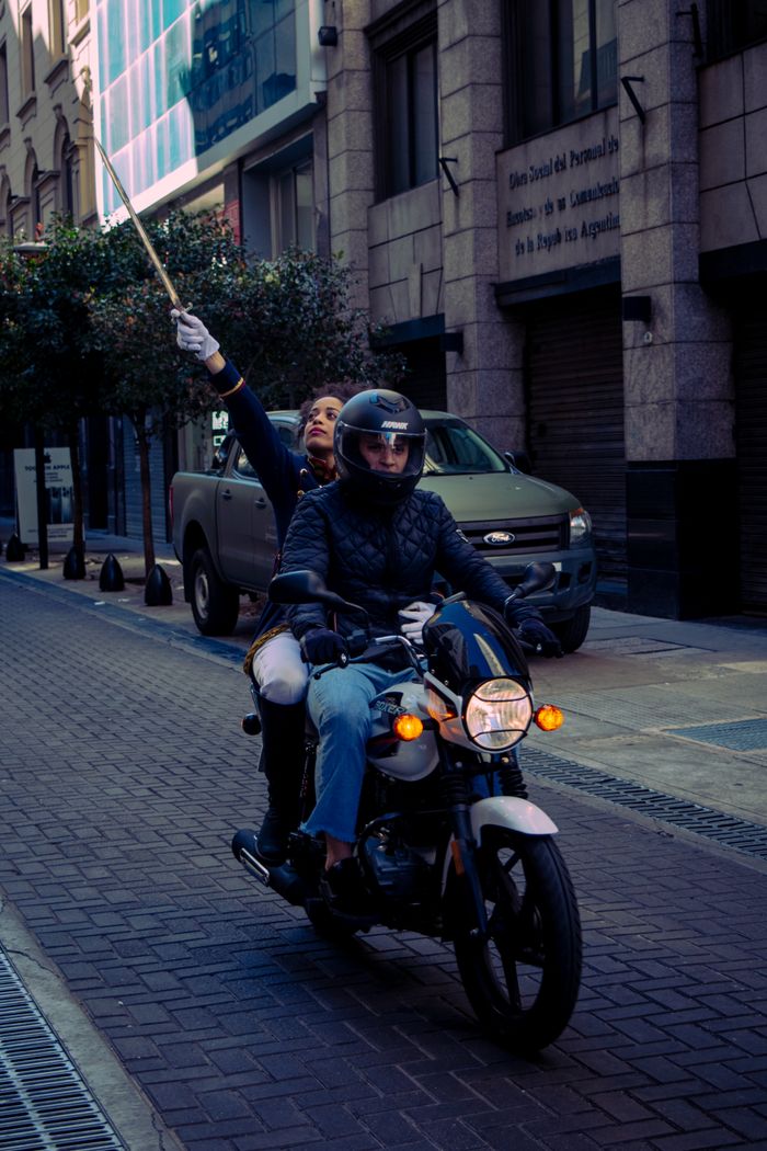 A pair riding a motorcycle down an urban street in Buenos Aires, capturing candid city life.