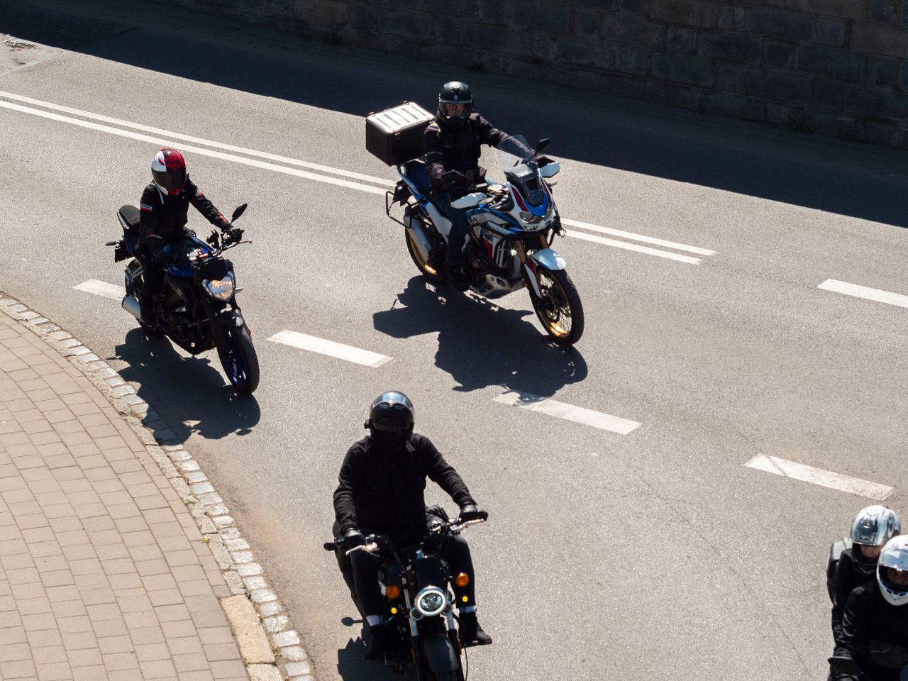A group of motorcyclists riding through the streets of Wrocław, Poland on a sunny day.