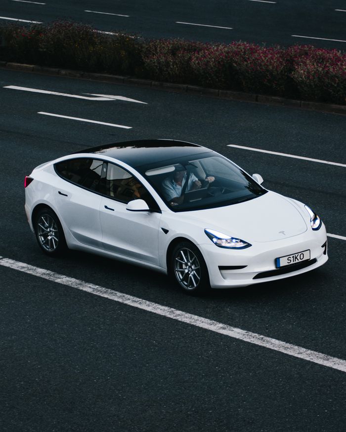 Tesla Model 3 driving on a highway in Osnabrück, Germany, showcasing modern electric vehicle design.